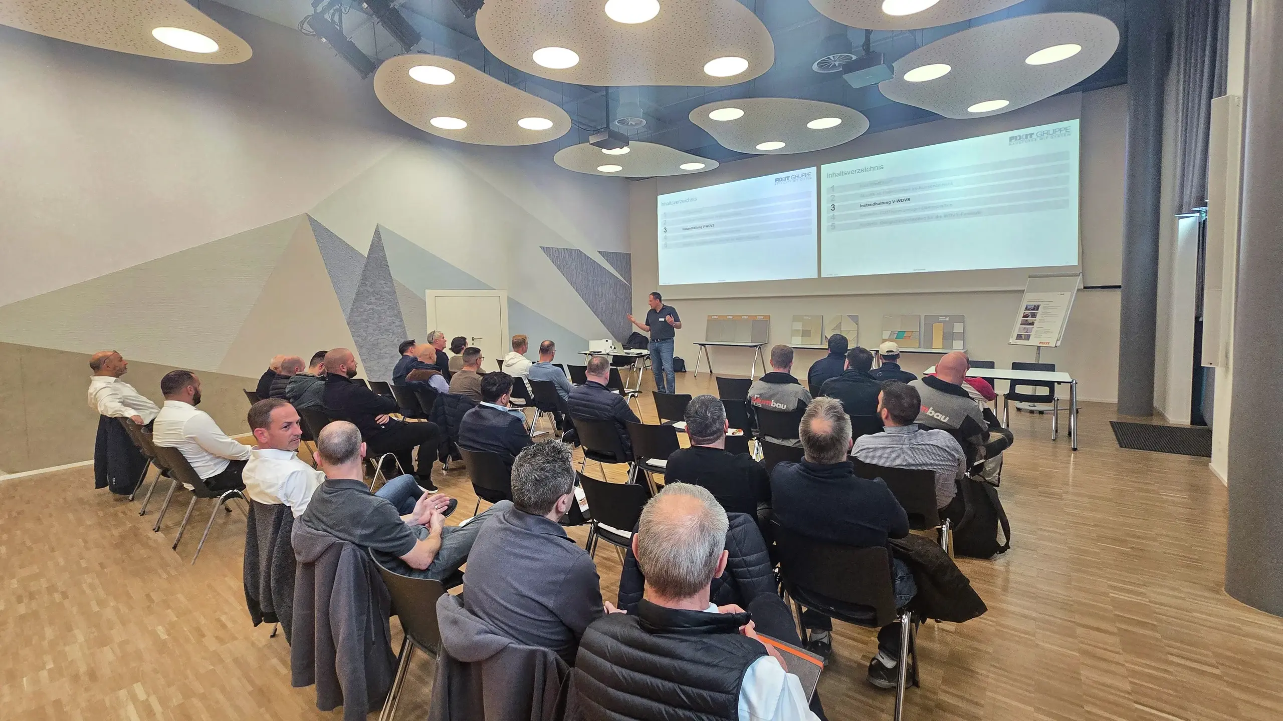 Ansicht auf alle Teilnehmenden, die in Reihen vor der Präsentation von Ralf Bannwitz sitzen