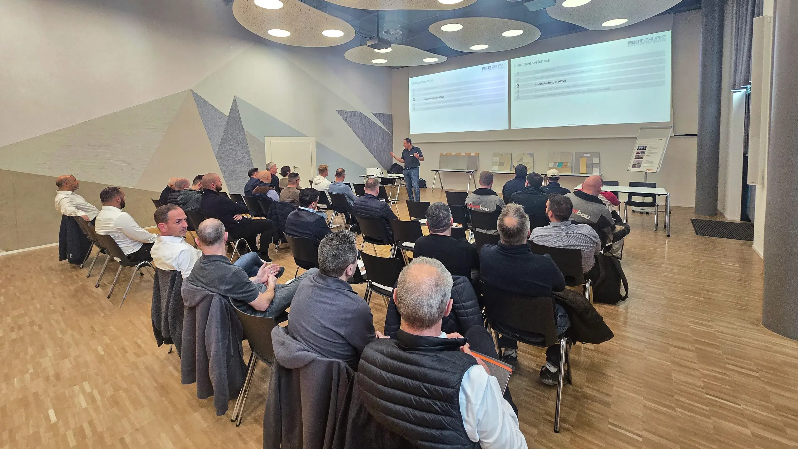 Ansicht auf alle Teilnehmenden, die in Reihen vor der Präsentation von Ralf Bannwitz sitzen