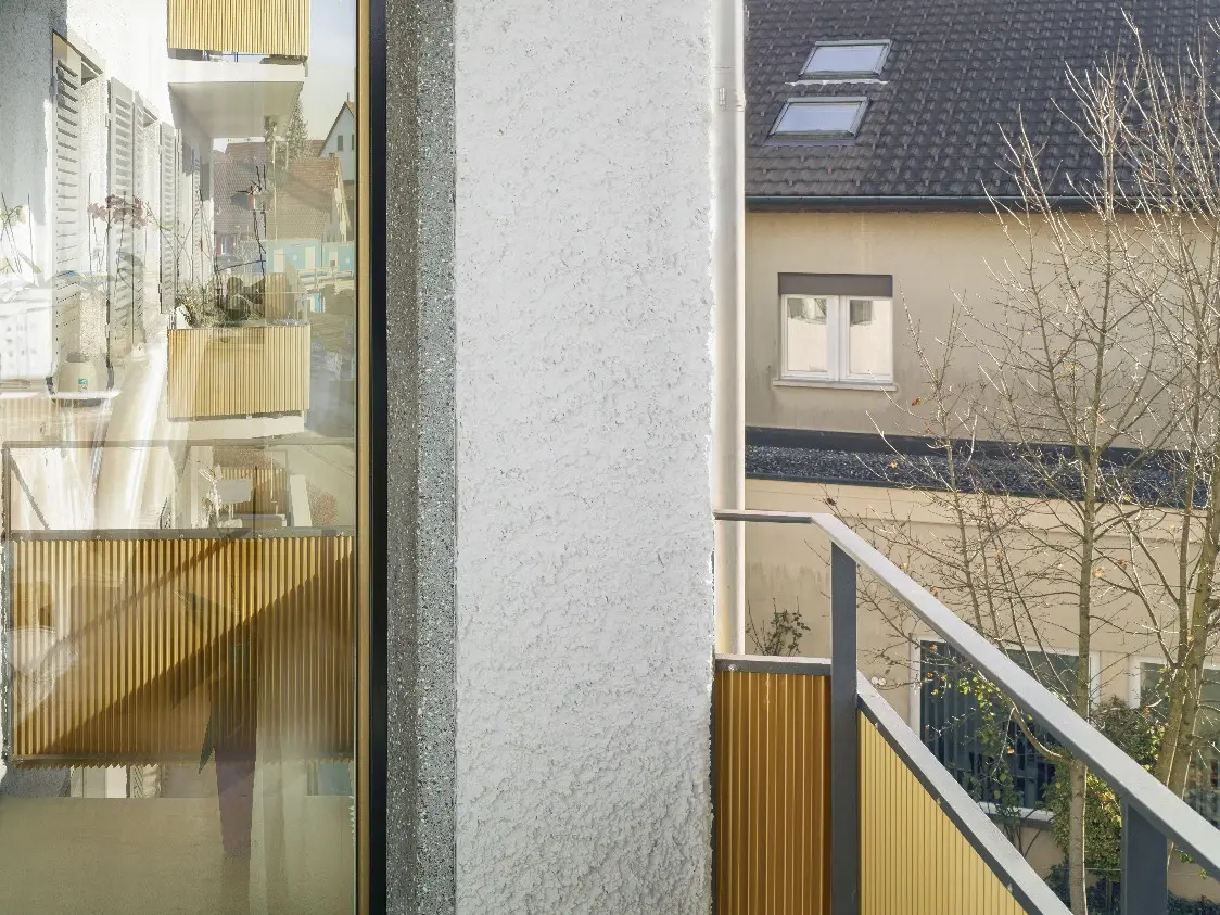 Detailansicht Balkoninnenbereich mit Balkontüre, gestreifter Markise und Geländer
