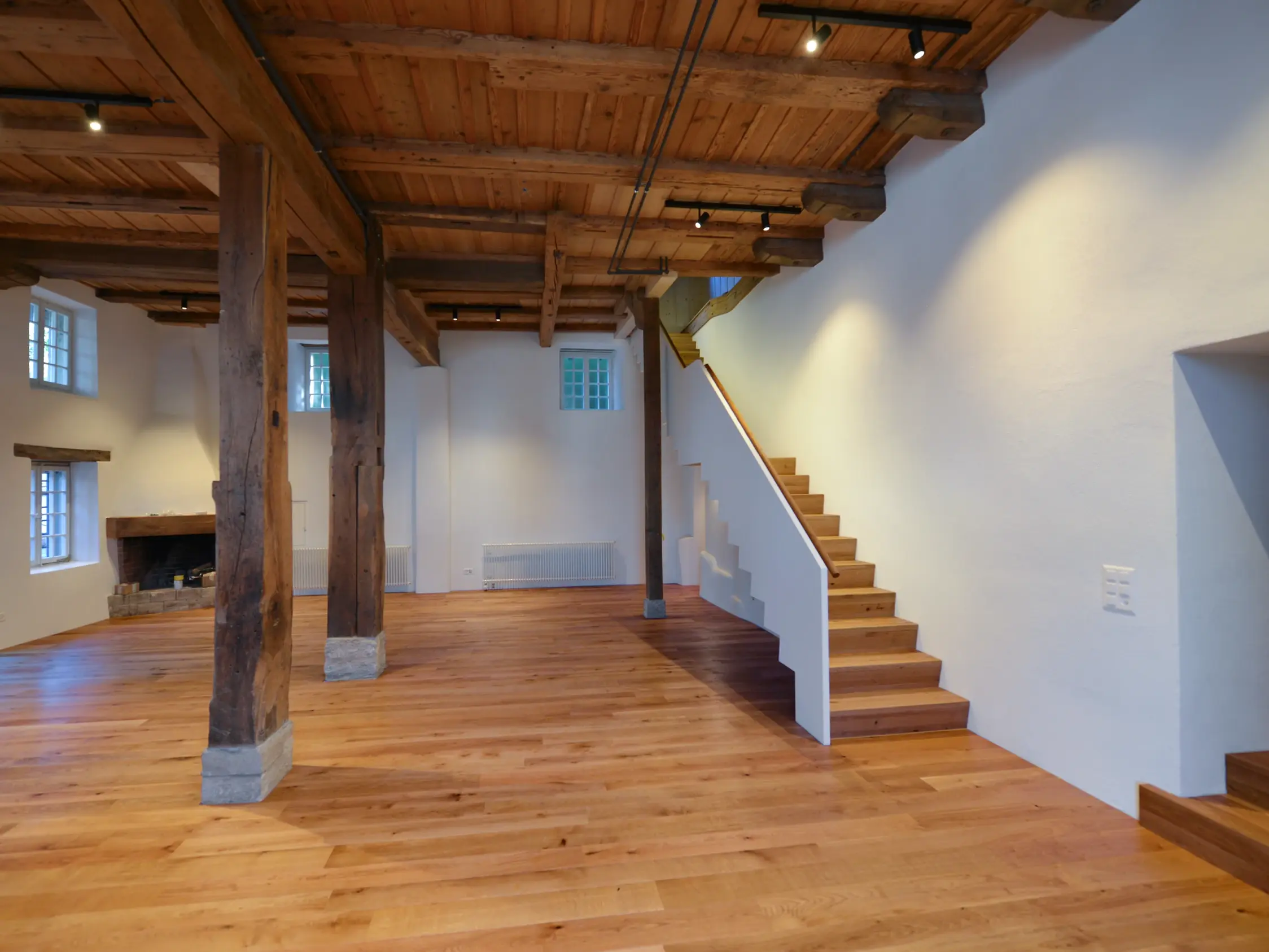 Vue depuis la porte vers l'intérieur avec les poutres apparentes et l'escalier menant à l'étage