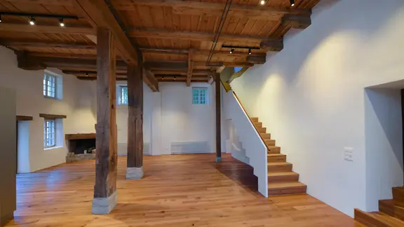 Innenraum mit Holzboden, Treppe und historischer Balkenstrukur der Mühle Madiswil und weiss verputzen Wänden mit Innendämmung aus Fixit 222 Aerogel Dämmputz