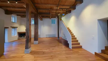 Innenraum mit Holzboden, Treppe und historischer Balkenstrukur der Mühle Madiswil und weiss verputzen Wänden mit Innendämmung aus Fixit 222 Aerogel Dämmputz