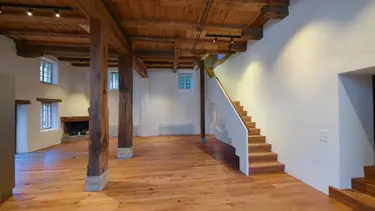 Intérieur avec plancher en bois, escalier et structure de poutres historiques du moulin de Madiswil et murs enduits en blanc avec isolation intérieure en Fixit 222 Aerogel