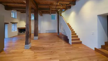Intérieur avec plancher en bois, escalier et structure de poutres historiques du moulin de Madiswil et murs enduits en blanc avec isolation intérieure en Fixit 222 Aerogel