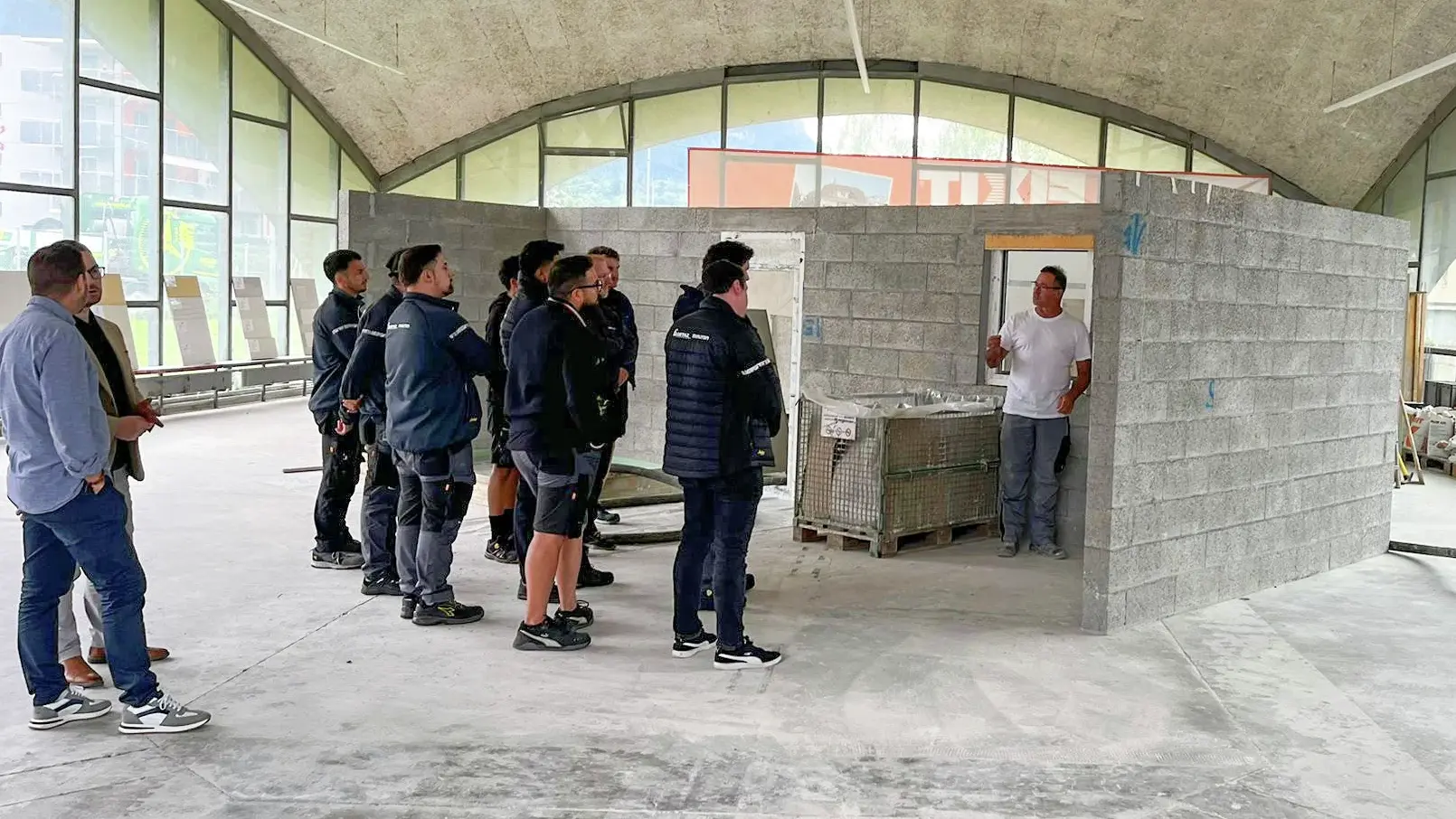 Le groupe des collaborateurs du magasin Getaz-Miauton SA se tient à gauche et un technicien d'application Fixit montre les points problématiques sur un mur d'échantillons.