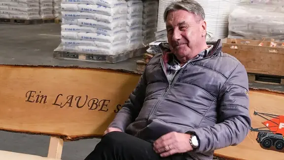 Markus Laube, collaborateur du service extérieur, sur son cadeau de retraite : un banc en tronc d'arbre pour le jardin