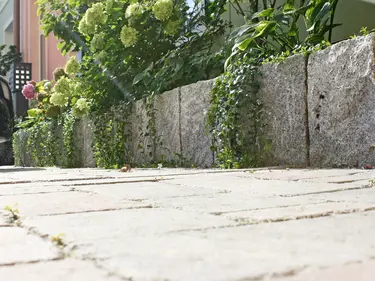 Ein Natursteinrand um ein Blumenbeet, der die Pflanzen elegant einfasst.