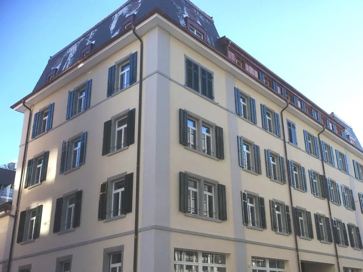 Edificio di cinque piani con intonaco giallo chiaro e persiane verdi