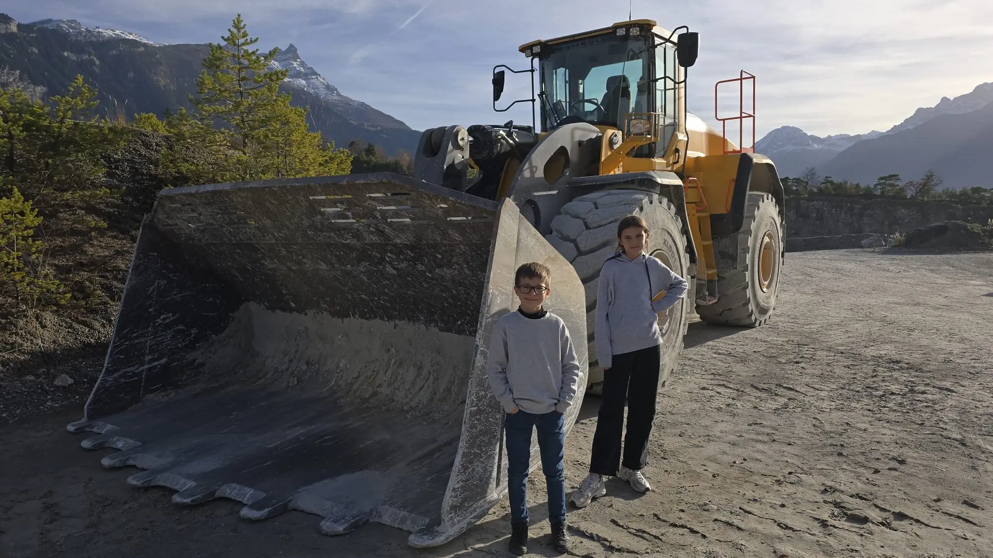 Die beiden Kinder vor einem grossen Schaufelbagger im Steinbruch in Bex