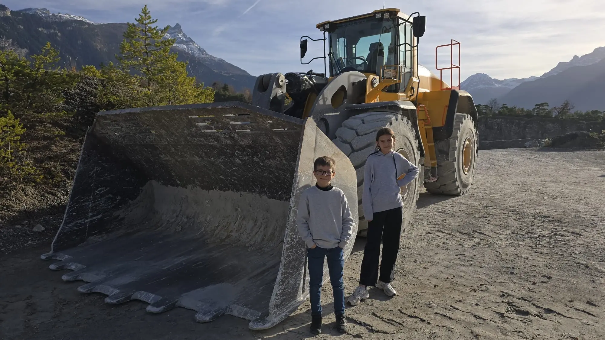 Die beiden Kinder vor einem grossen Schaufelbagger im Steinbruch in Bex