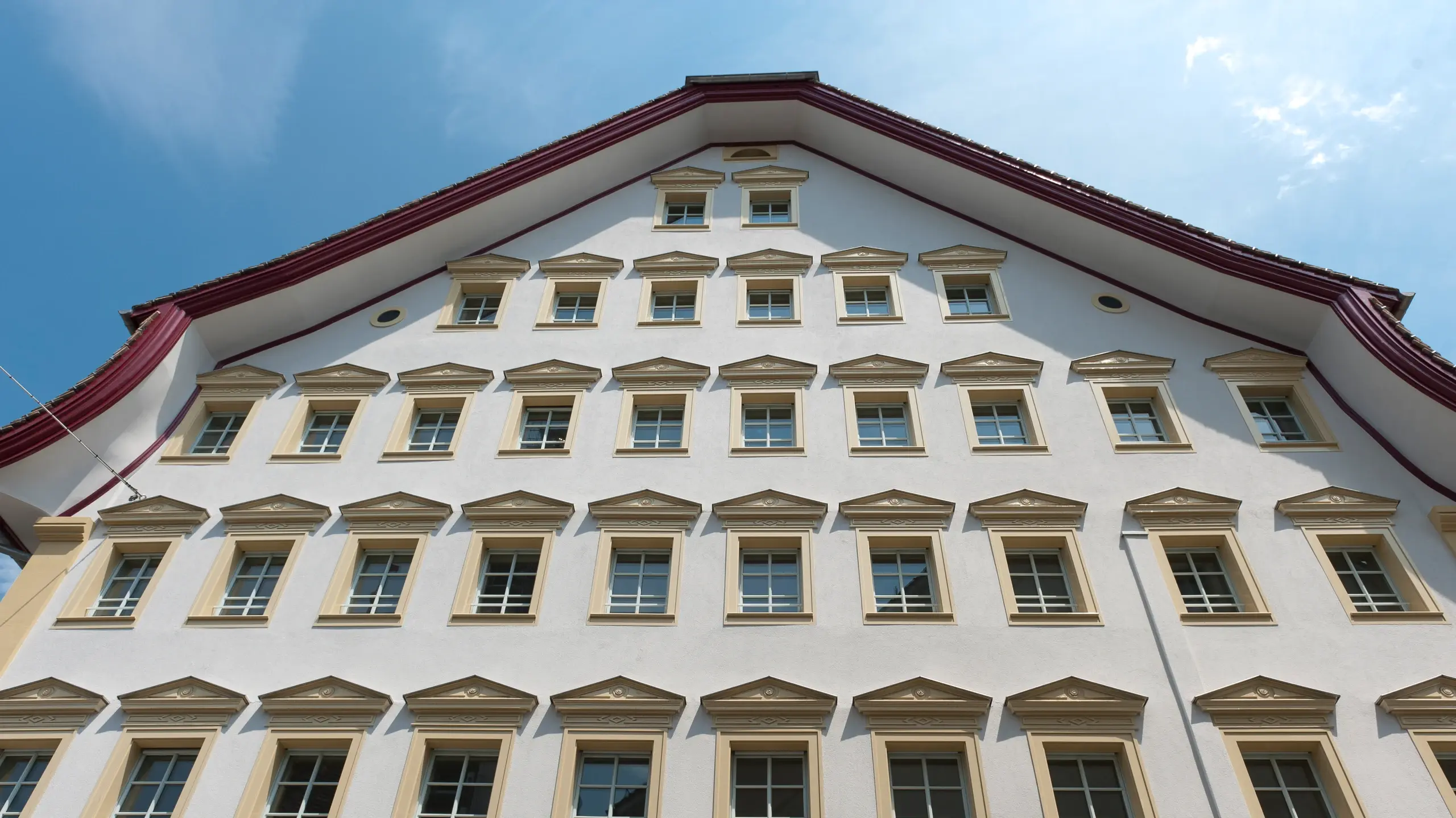 Façade à pignon d'un bâtiment historique avec de très nombreuses petites fenêtres, chacune dotée d'un auvent.