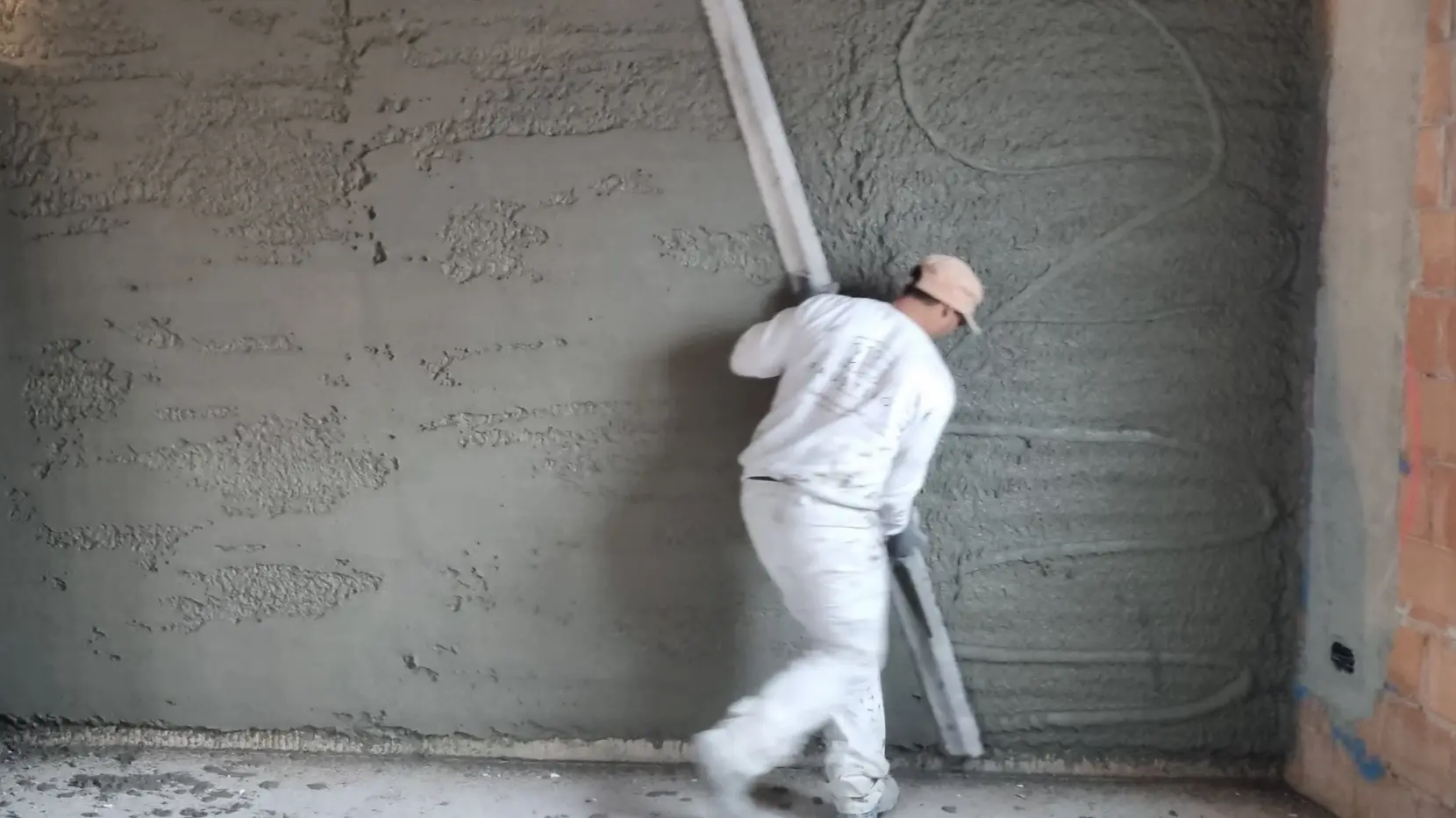 Ein Verarbeiter zieht mit einer langen Latte den Fixit 600 Rapid an der Innenwand glatt