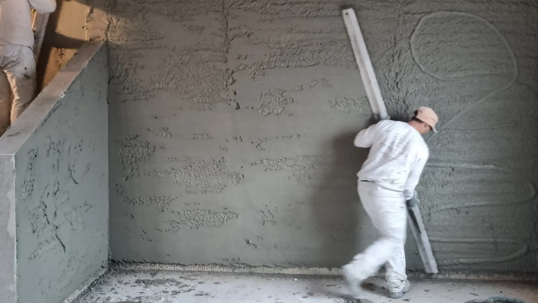 Ein Verarbeiter zieht mit einer langen Latte den Fixit 600 Rapid an der Innenwand glatt