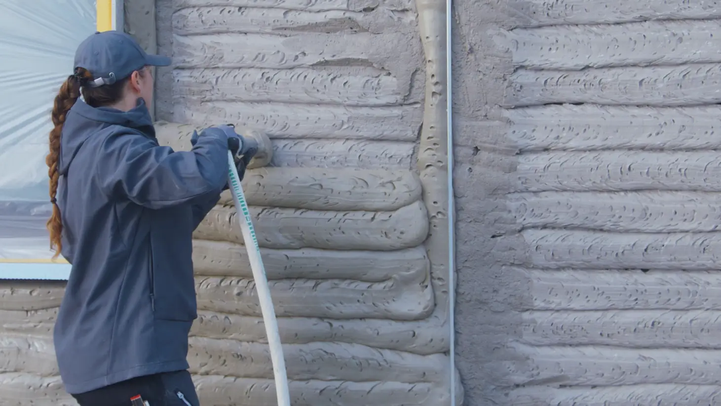 Georgia Häseli applique l'enduit isolant FOME® sur un mur.