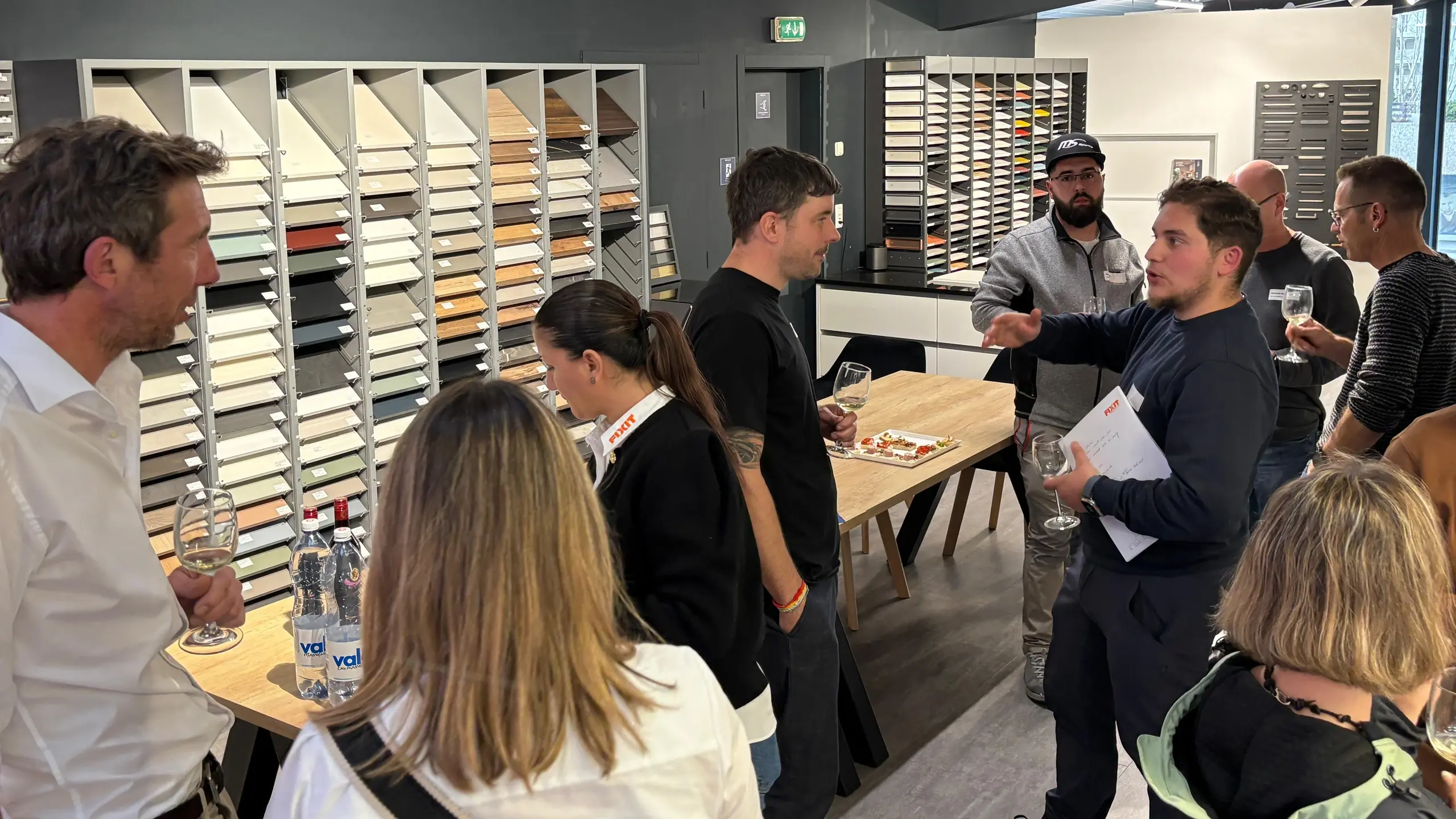 Mehrere Personen sind miteinander im Gespräch, Materialmuster sind im Hintergrund zu sehen