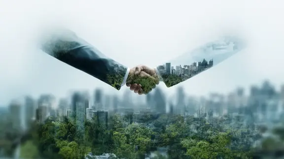 Partnerschaften für den Wandel – im Vordergrund ein Händedruck, im Hintergrund eine nachhaltige Stadt.