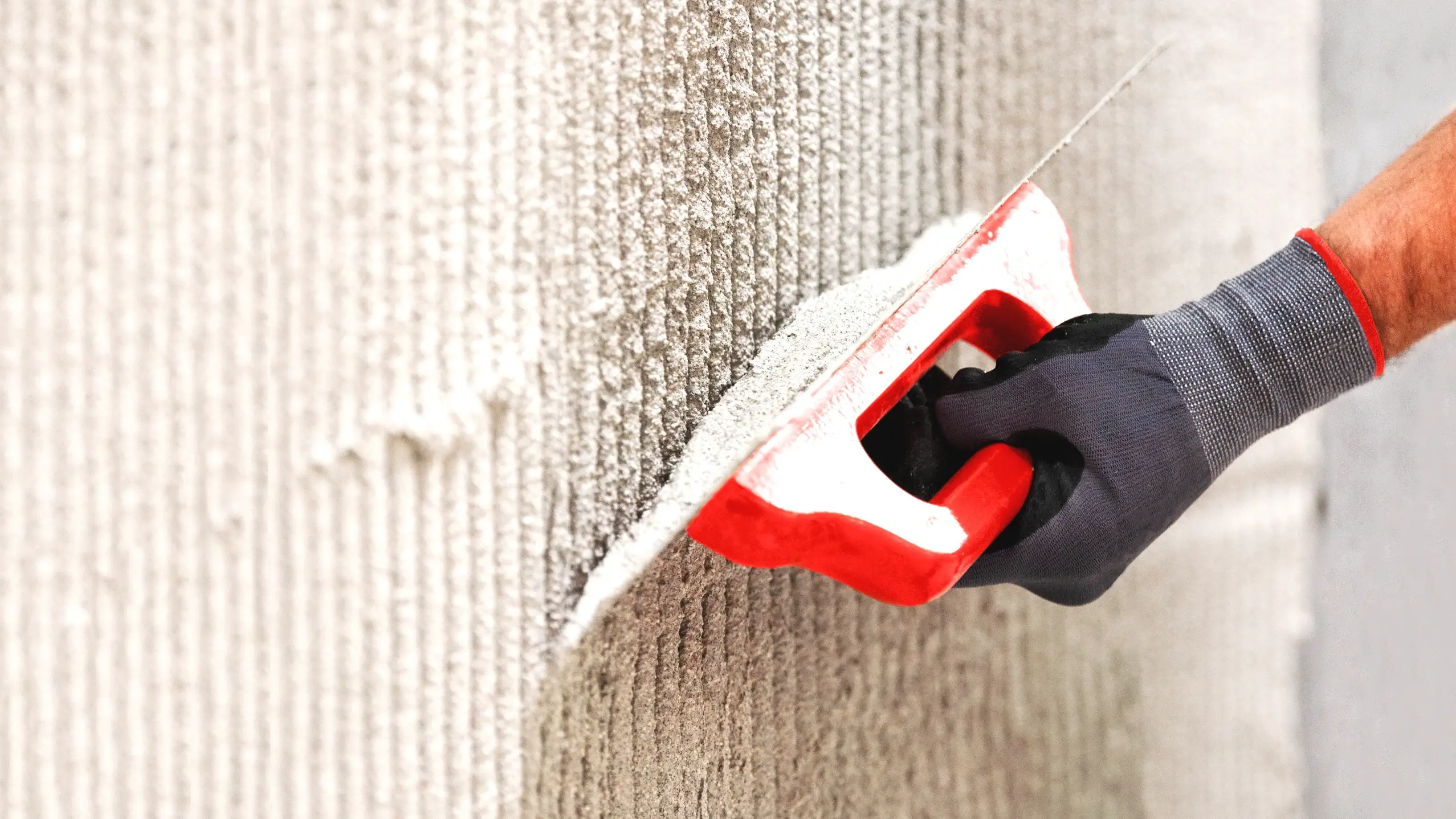 Gekämmter Putz mit einer Traufel und einer Hand, die den Putz aufzieht