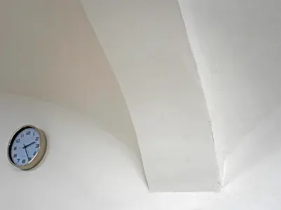 Sanierter Deckenbereich in weißer Farbe mit einer Uhr an der Wand.