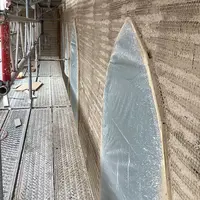 : Das Gebäude während der Bauphase – eingerüstet von außen, mit Detailaufnahmen der Dämmputzverarbeitung an den Fensterbereichen.