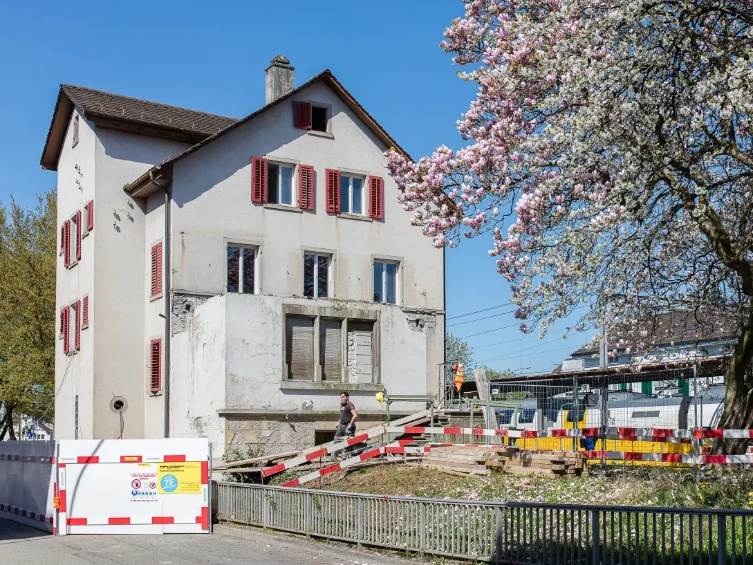 Mehrfamilienhaus vor der Sanierung mit Absperrung im Sonnenschein