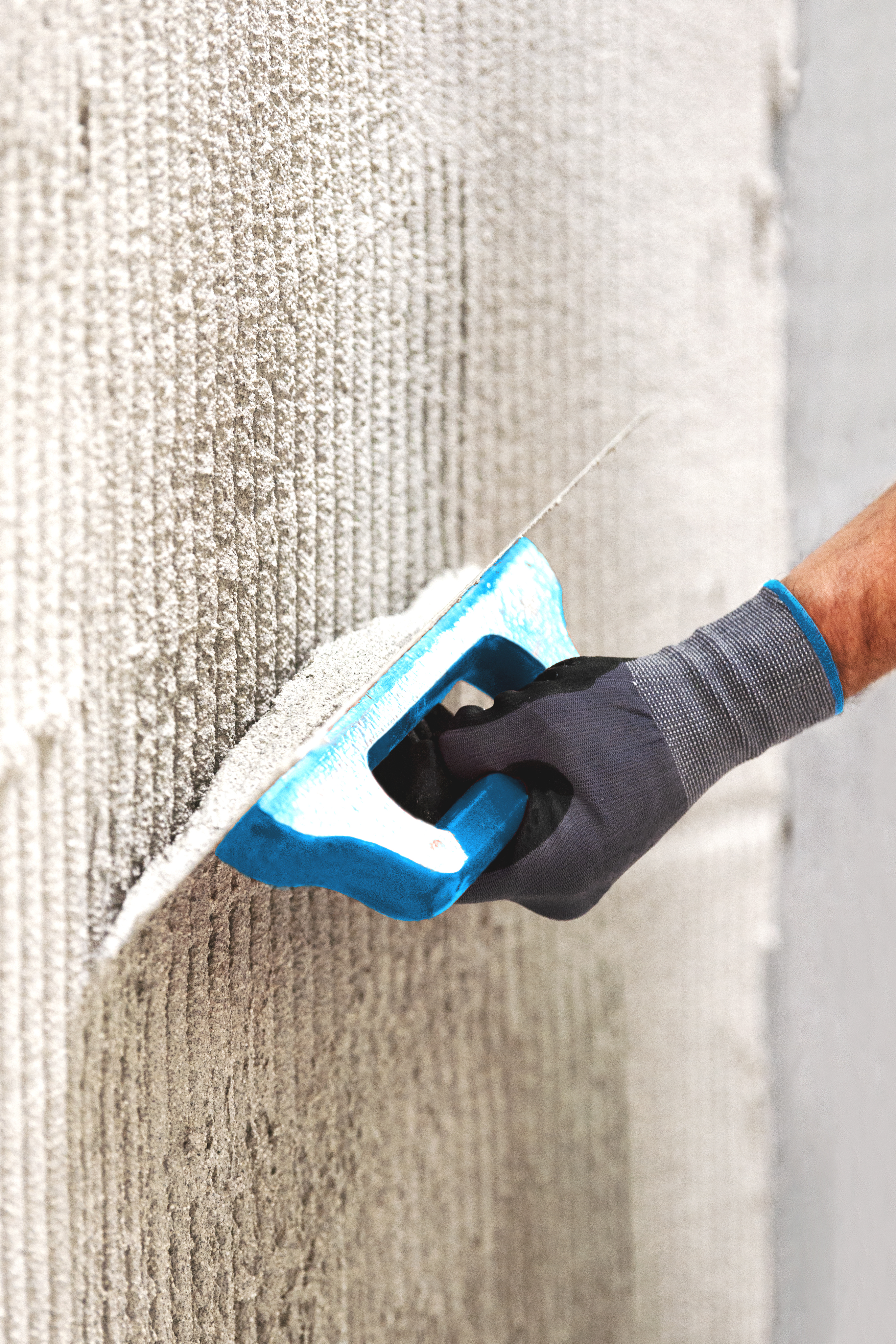 Worker works reinforcing mesh into the surface of the plaster