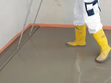 Ein Verarbeiter glättet eine Schicht Estrich auf dem Boden