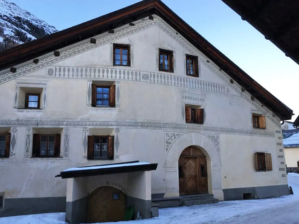 Stirnseite der unsanierten Fassade des Chesa Palmira  in der Dämmerung mit Schnee 