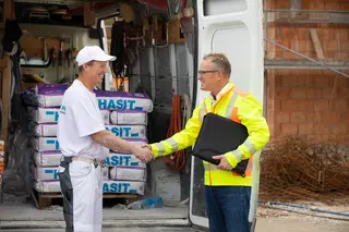 Ein HASIT-Vertriebsmitarbeiter begrüßt einen Kunden auf einer Baustelle und schüttelt ihm die Hand