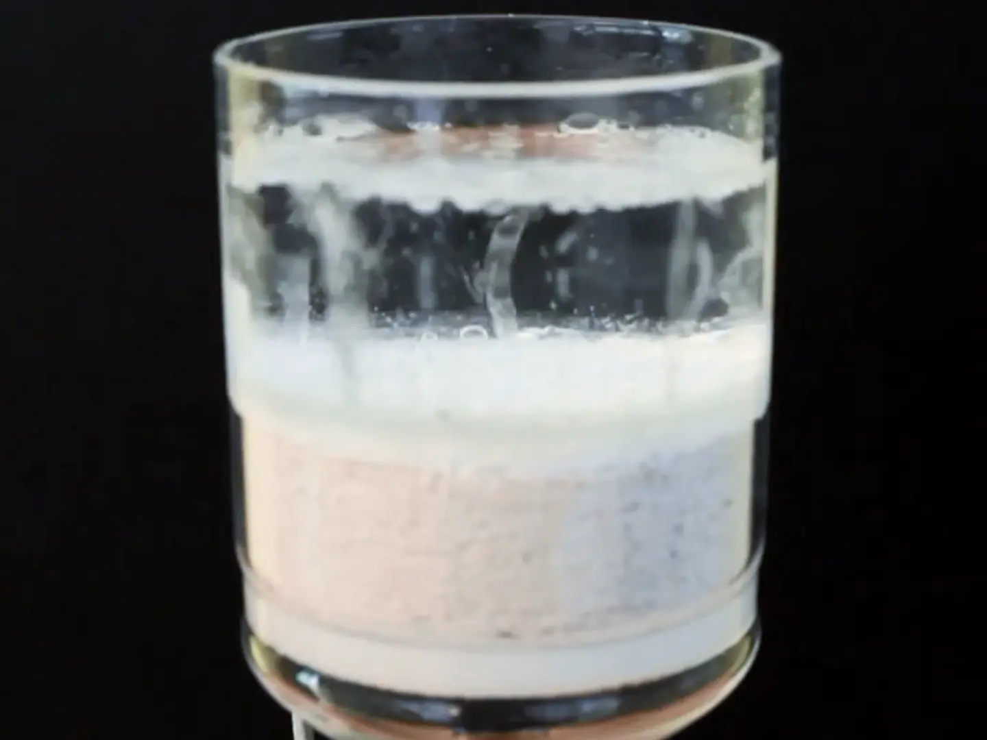 Vue détaillée du récipient d'essai : en bas, enduit isolant Fixit 222 Aerogel et, au-dessus, de l'eau contenant des bulles d'air pénétrantes.