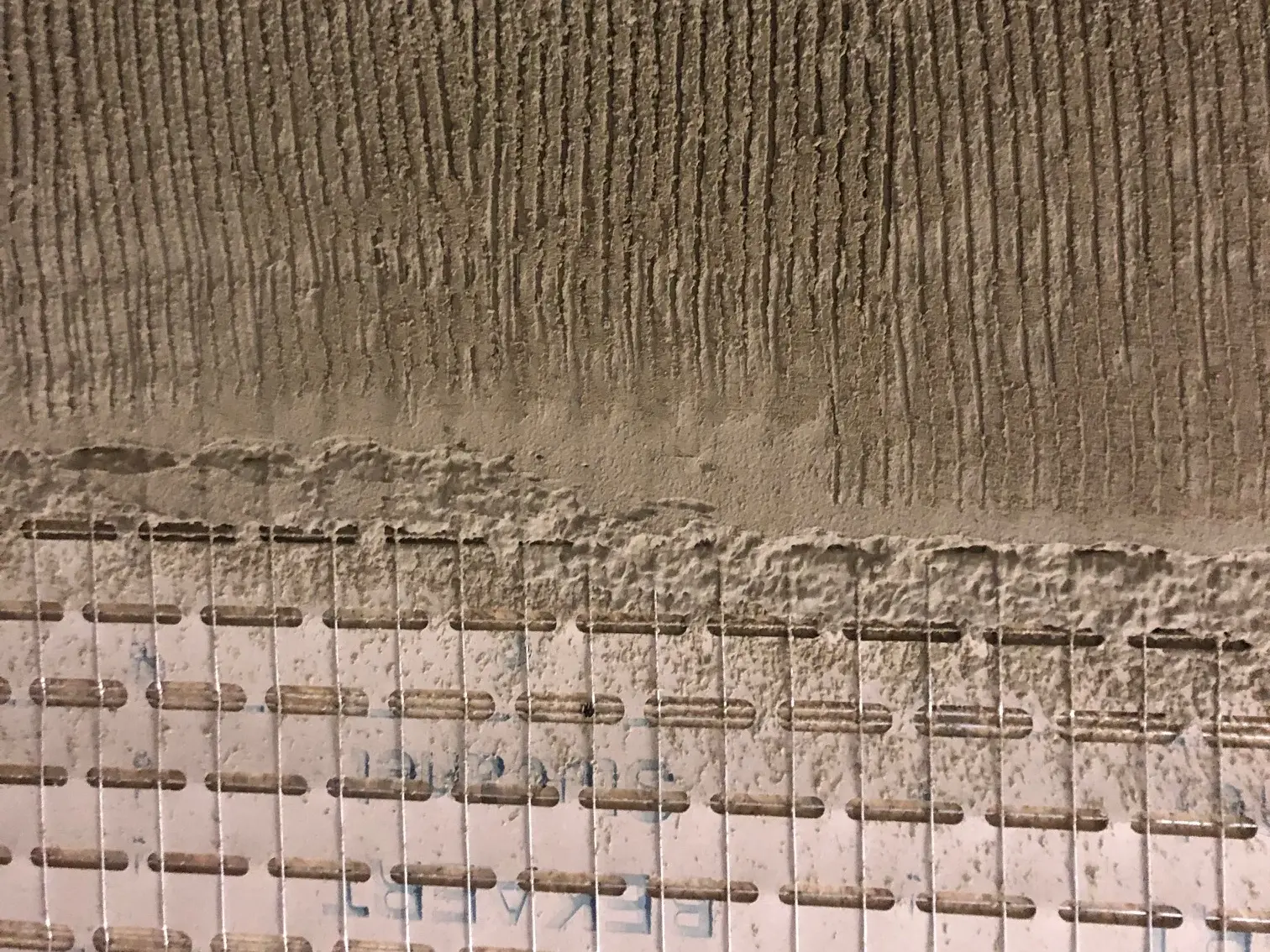 Stucanet® Putzträgergitter mit aufgezogenem, gekämmten Putz im oberen Bereich