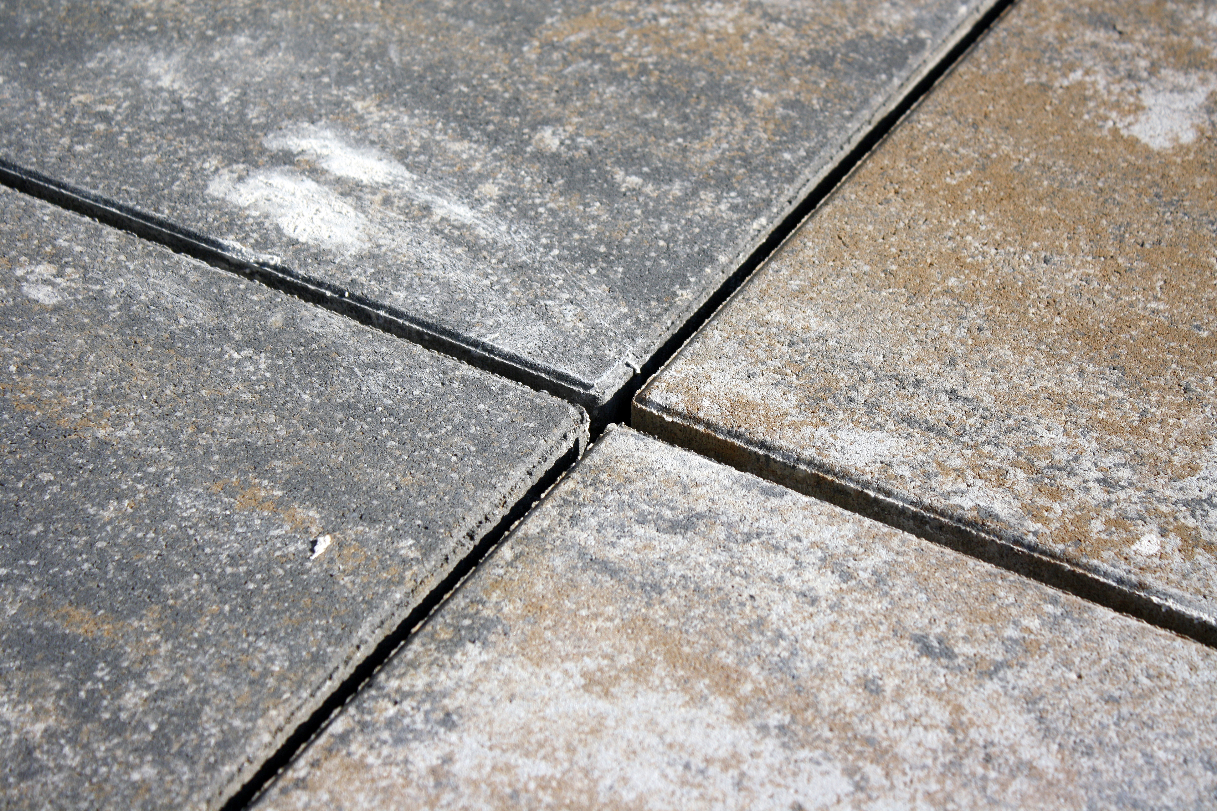 Eine Nahaufnahme von Fliesen im Außenbereich, die gleichmäßig verlegt sind. Die Struktur der Fliesenoberfläche sowie die feinen Fugen dazwischen sind gut sichtbar