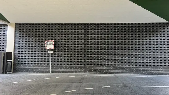 Zone d'entrée de la tour de la foire de Zurich avec maçonnerie apparente, mortier de maçonnerie Fixit 987 coloré et structure perforée en arrière-plan sur le mur.