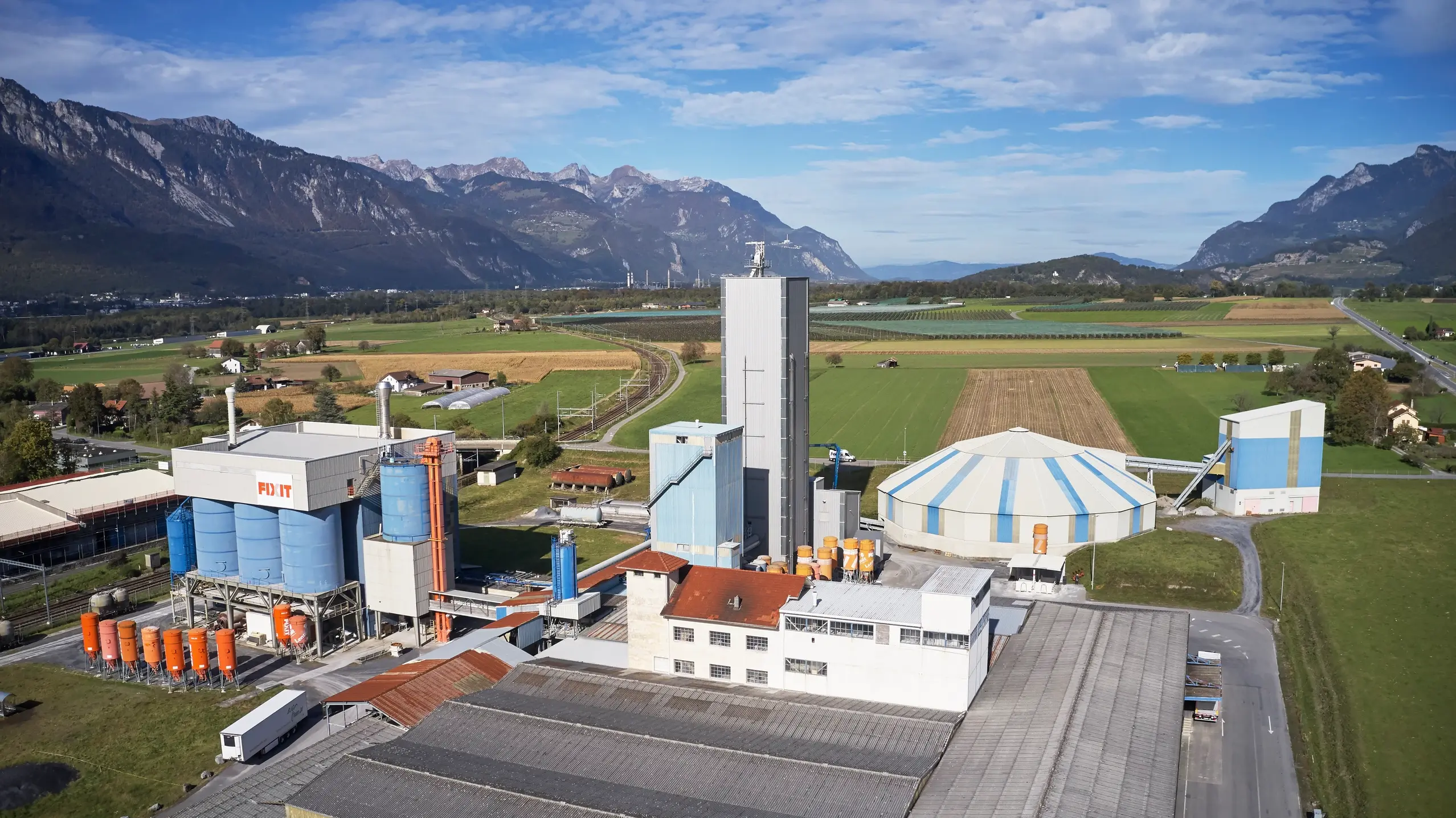 Vue aérienne de l'usine de production de Fixit AG à Bex, avec le hall de stockage de pierres, les zones d'entreposage et les silos Fixit