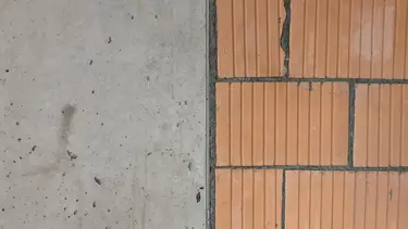 Eine Wand aus links Beton und rechts mit angrenzendem Backsteinmauerwerk