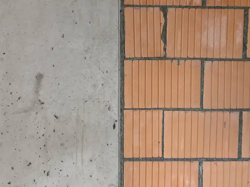 Le mur en béton rencontre la maçonnerie en briques