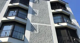 Vue détaillée de la façade extérieure en crépi gris avec des accents blancs et des fenêtres particulières