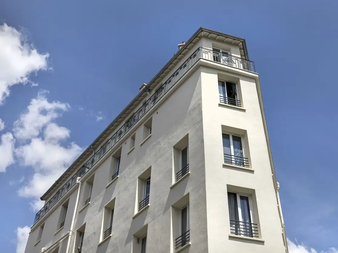 Froschperspektive nach oben, das Gebäude bildet ein schmales Dreieck, die Eckseite ist nur etwas breiter als ein Fenster