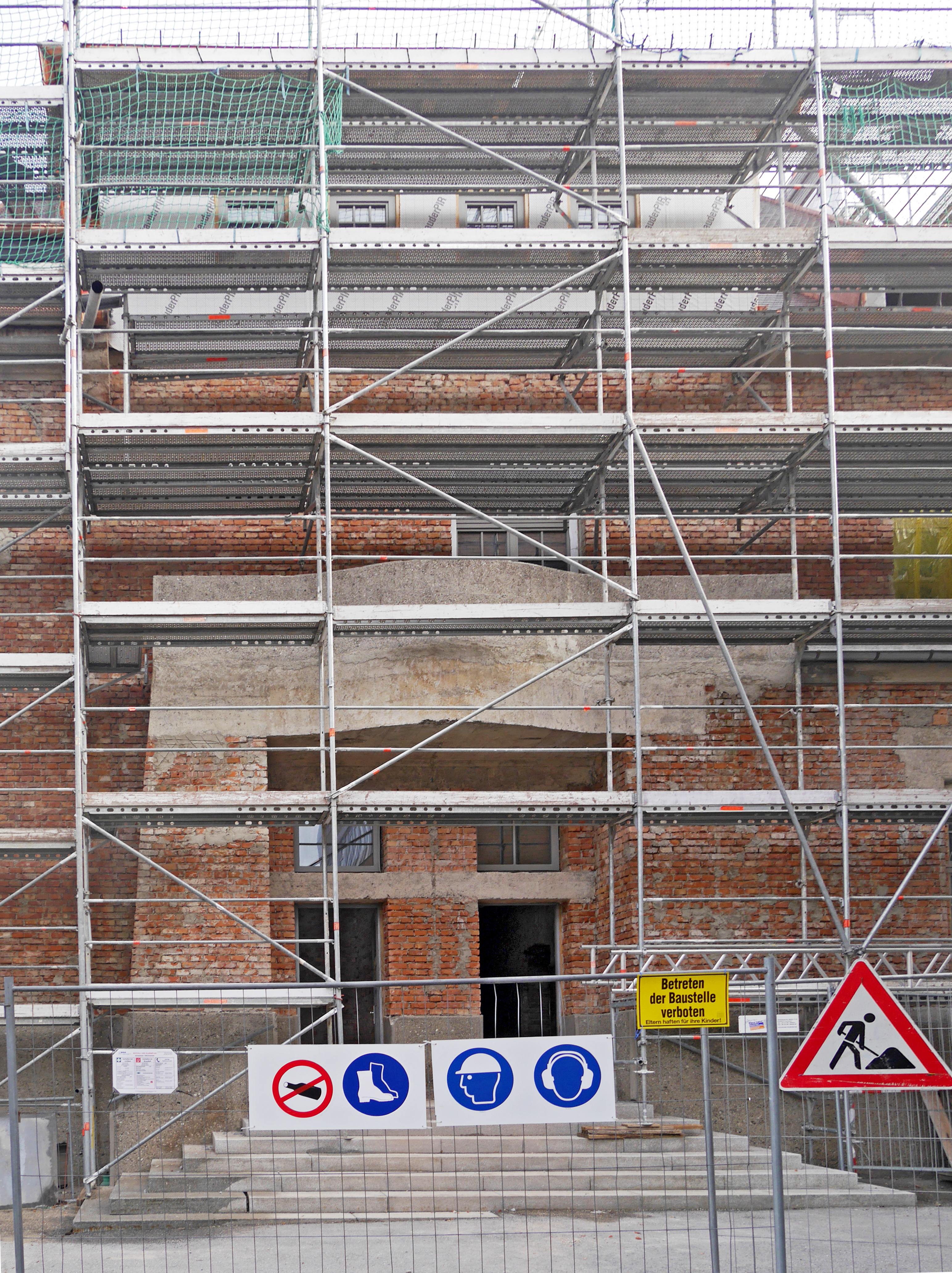 Die Außenfassade einer Baustelle ist mit einem Baugerüst versehen