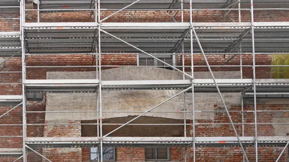 Die Außenfassade einer Baustelle ist mit einem Baugerüst versehen