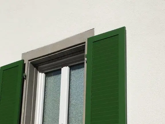 Ein Fenster nach der Sanierung mit grasgrünen Fensterläden