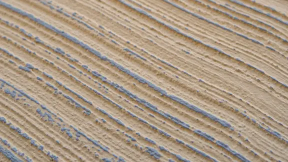 Detailaufnahme einer Besenstrich Putzstruktur in Beige mit taubenblauem Highlight