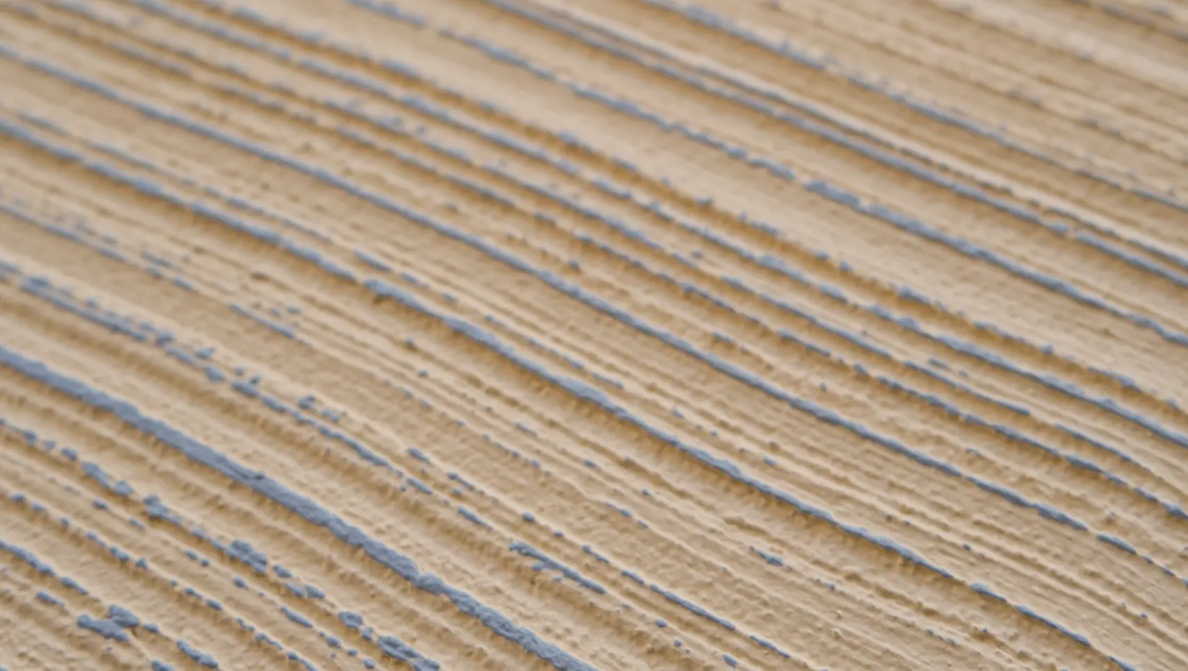 Gros plan d'un crépi brossé beige avec des reflets bleu pigeon