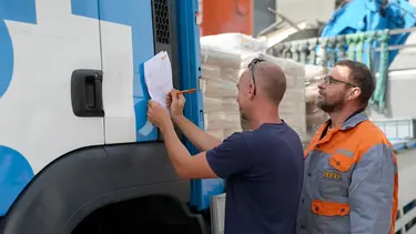 Fixit Logistikmitarbeiter übergibt die Ware an den LKW-Fahrer