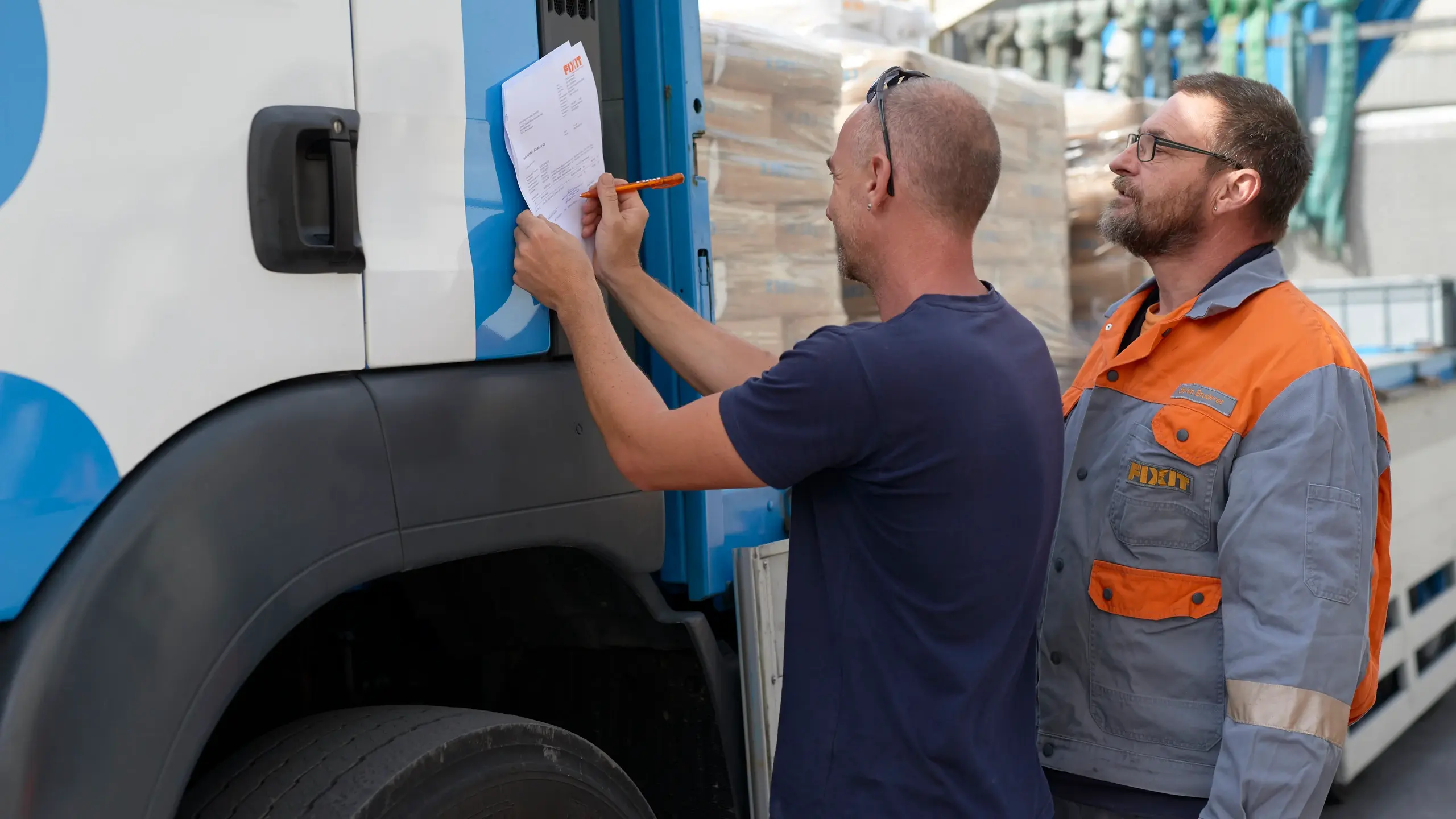 Fixit Logistikmitarbeiter übergibt die Ware an den LKW-Fahrer