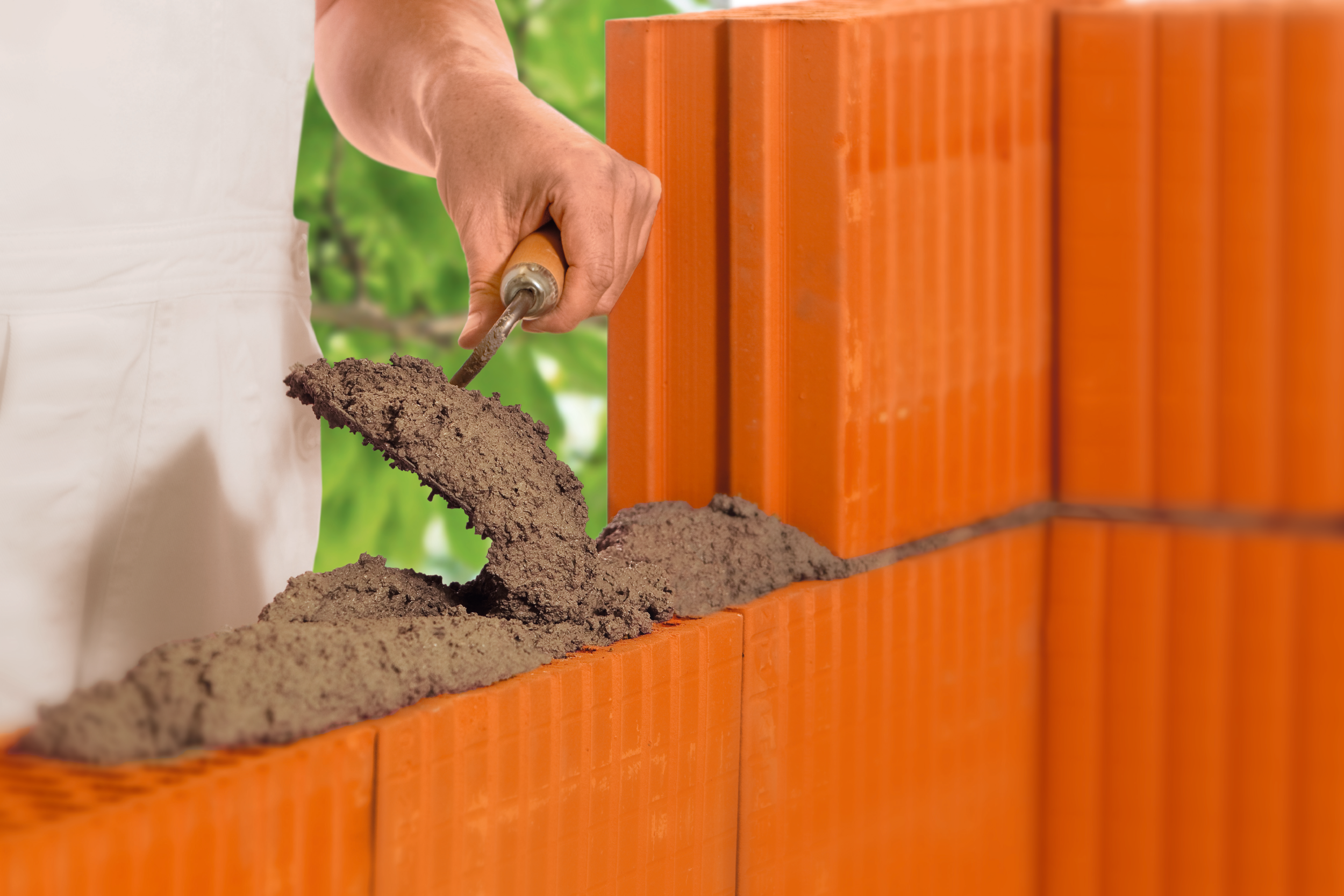 Eine Schicht Mauermörtel wird auf Ziegelsteine aufgetragen