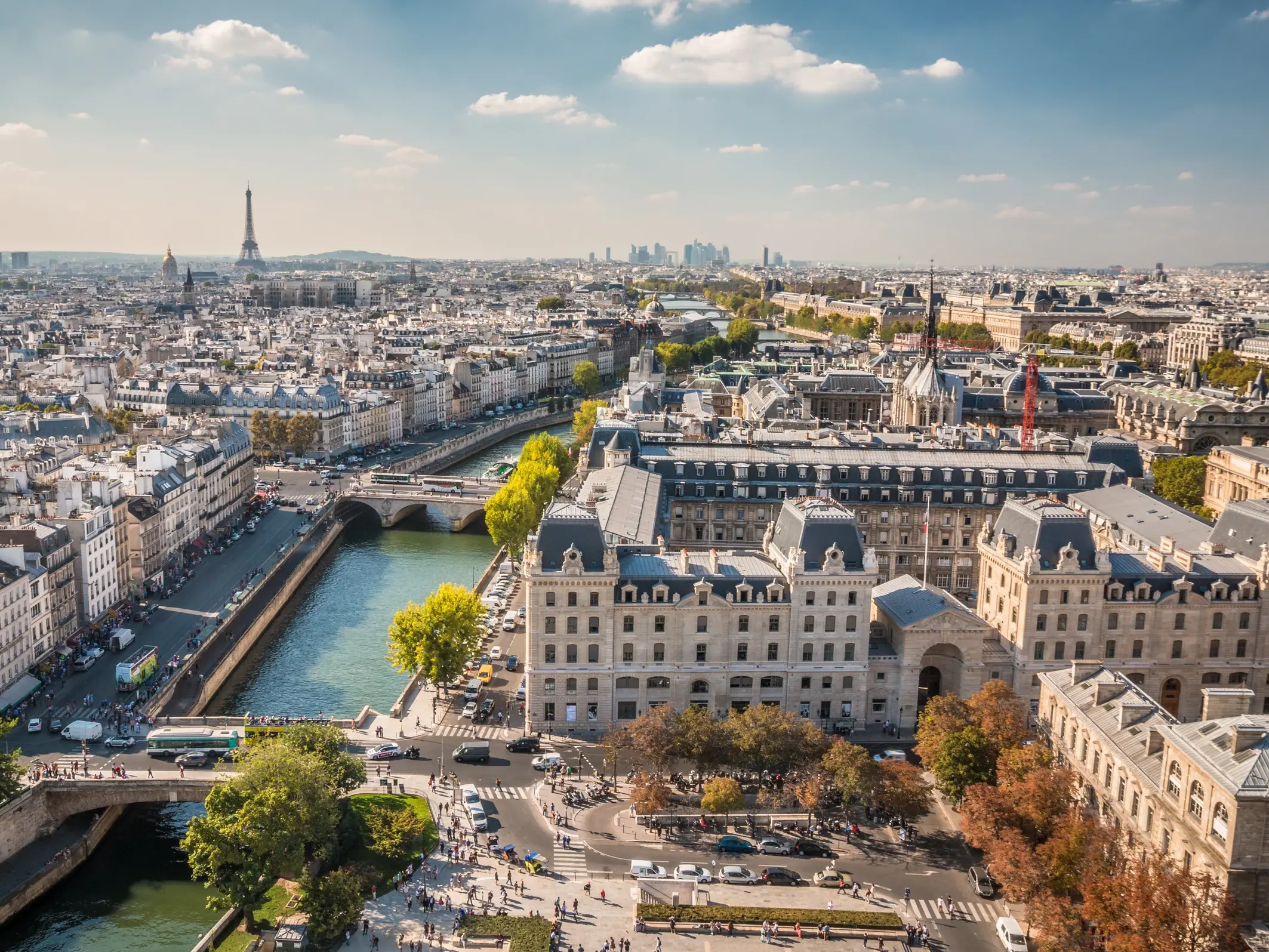 Ansicht der Stadt Paris aus der Vogelperspektive mit historischen Mehrfamilienhäusern im Vordergrund, der Seine in der Mitte und klein im Hintergrund der Eiffelturm