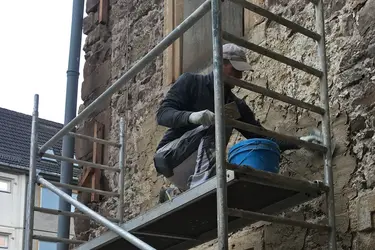 Ein Arbeiter verputzt die Außenwand.