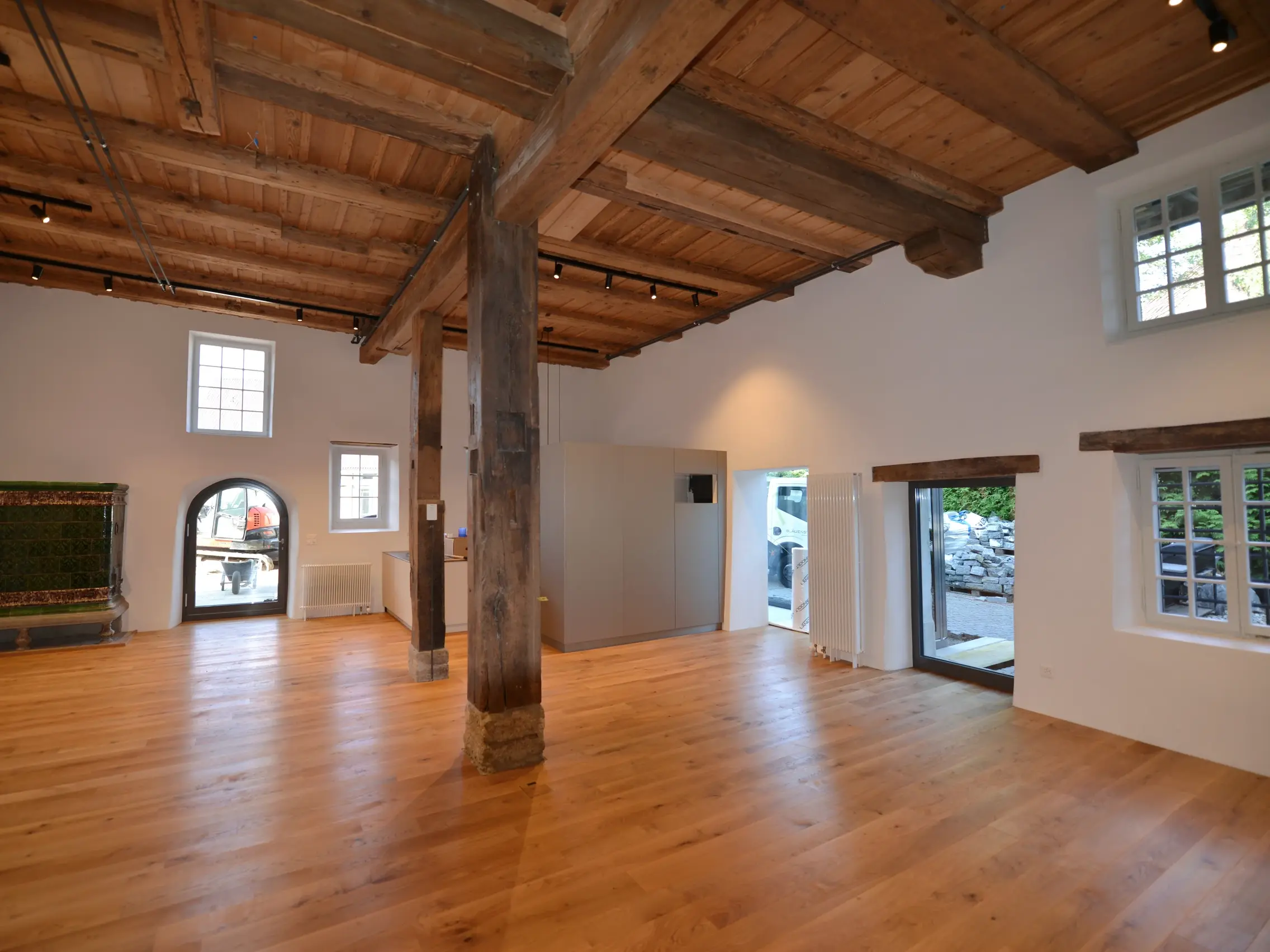 Intérieur avec poutres apparentes au centre, murs enduits de blanc et ouvertures de fenêtres historiques