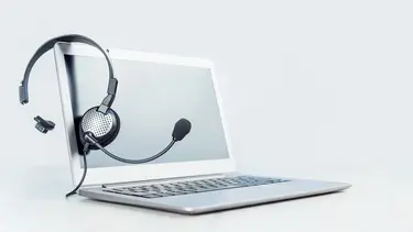 Silberner Laptop mit Headset über dem Bildschirm