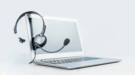 Silberner Laptop mit Headset über dem Bildschirm